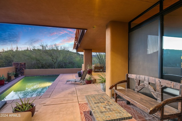 patio terrace at dusk featuring a fenced in pool