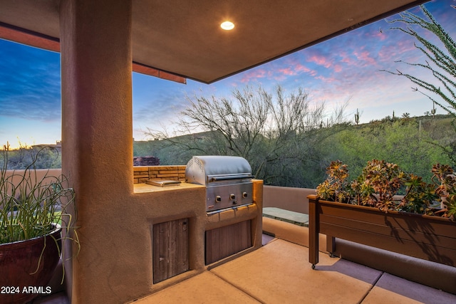 patio terrace at dusk featuring exterior kitchen and grilling area