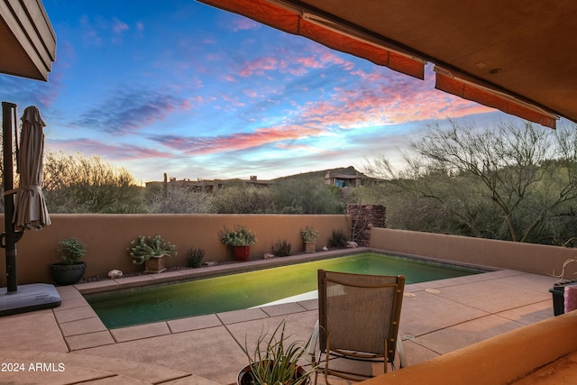 pool at dusk with a patio area