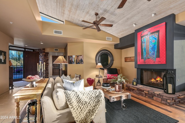 living room with ceiling fan, vaulted ceiling, wooden ceiling, a fireplace, and light wood-type flooring