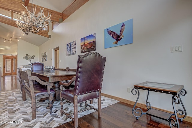 dining room with beam ceiling, a notable chandelier, hardwood / wood-style floors, a high ceiling, and baseboards