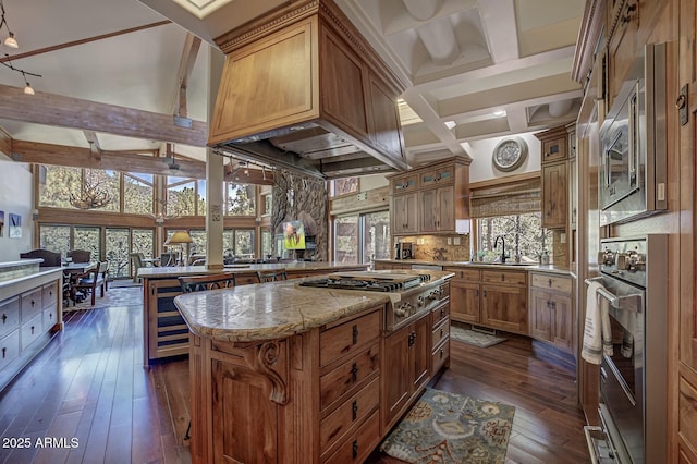 kitchen featuring appliances with stainless steel finishes, brown cabinetry, dark wood-style floors, tasteful backsplash, and beamed ceiling