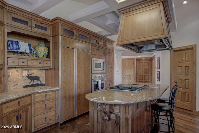 kitchen featuring built in appliances, light stone counters, dark wood-style flooring, and custom range hood