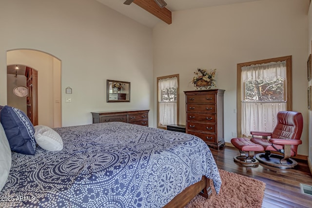 bedroom featuring baseboards, arched walkways, beamed ceiling, wood finished floors, and high vaulted ceiling