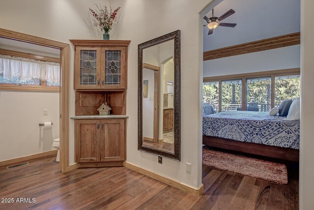 interior space featuring ceiling fan, wood finished floors, visible vents, and baseboards