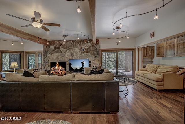 living area featuring wood-type flooring, ceiling fan, rail lighting, a fireplace, and beam ceiling