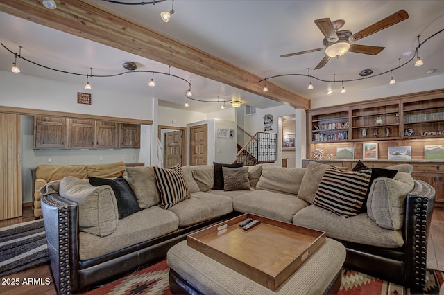 living room with a ceiling fan, stairway, beamed ceiling, and wood finished floors