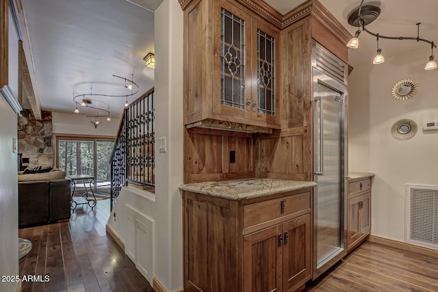 bar featuring dark wood-style flooring, visible vents, stainless steel built in fridge, and stairs