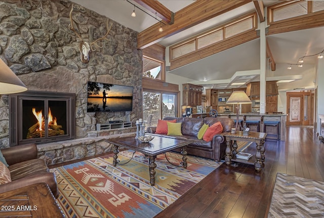 living area with high vaulted ceiling, a stone fireplace, beamed ceiling, and hardwood / wood-style flooring