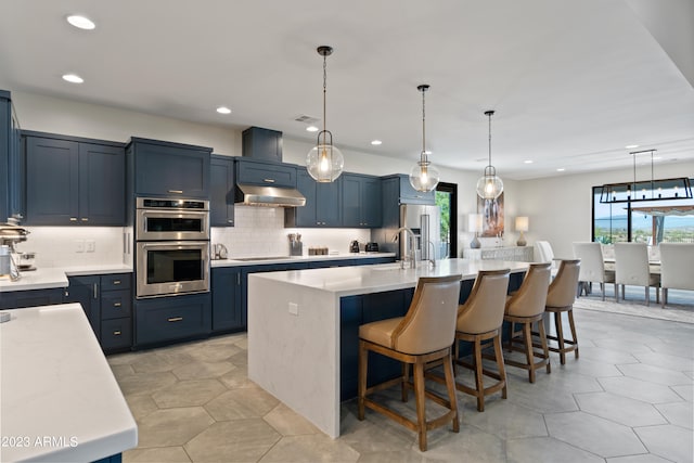 kitchen with a kitchen breakfast bar, hanging light fixtures, a large island with sink, blue cabinetry, and stainless steel appliances