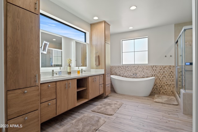 bathroom with a healthy amount of sunlight, tile walls, independent shower and bath, and vanity