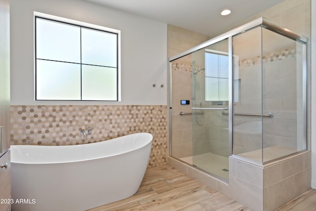 bathroom featuring tile walls, hardwood / wood-style floors, and plus walk in shower