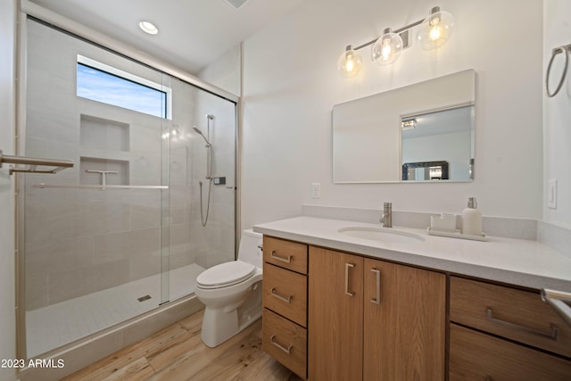 bathroom with hardwood / wood-style floors, vanity, toilet, and an enclosed shower