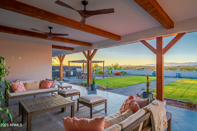 patio terrace at dusk featuring ceiling fan, an outdoor living space, a yard, and a water view