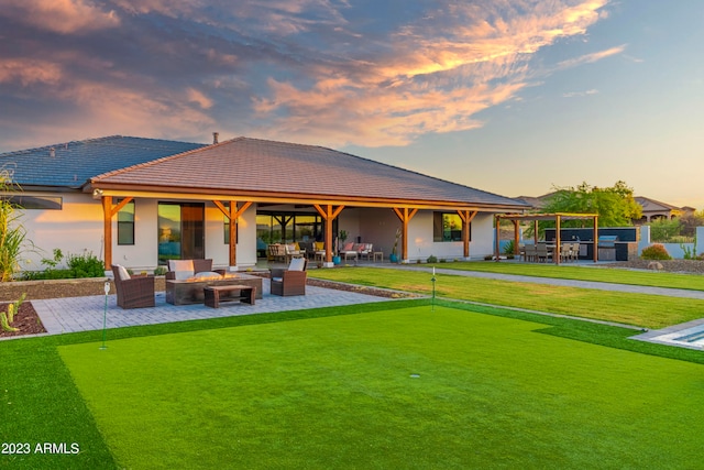 back house at dusk featuring outdoor lounge area, a patio area, and a yard