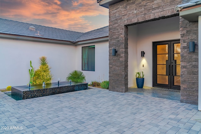 exterior entry at dusk with a patio and french doors