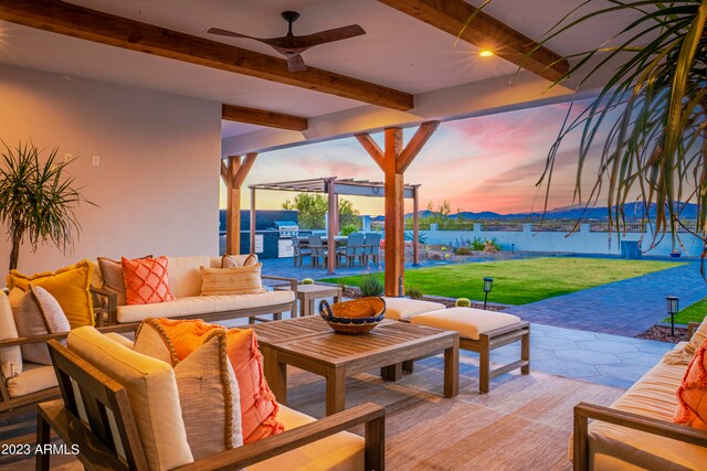 patio terrace at dusk with ceiling fan, an outdoor living space, a lawn, and a water view