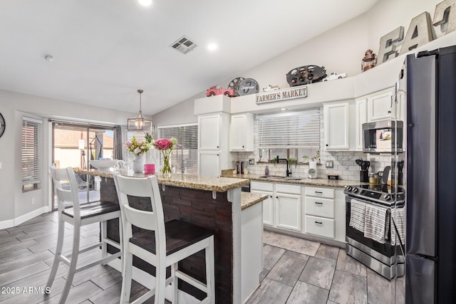 kitchen with sink, decorative light fixtures, a center island, stainless steel appliances, and white cabinets