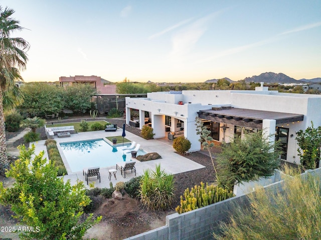 back house at dusk featuring a fenced in pool, a pergola, a patio area, and a mountain view