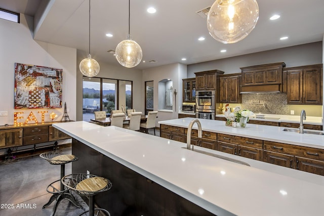 kitchen featuring dark brown cabinetry, sink, a breakfast bar area, and hanging light fixtures