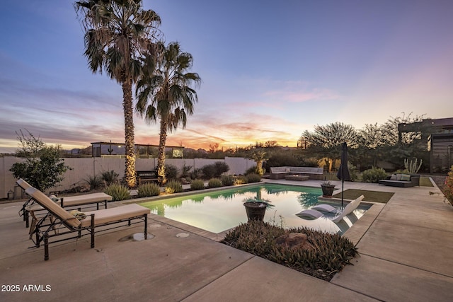 pool at dusk featuring a patio