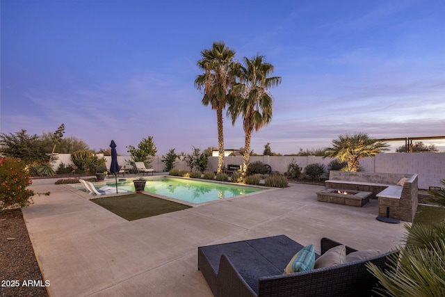 pool at dusk with a patio and an outdoor living space with a fire pit