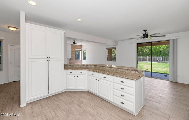 5787 W Barbara Ave, Glendale, AZ 85302 - kitchen featuring a ceiling fan, a peninsula, light stone countertops, white cabinets, and light wood-type flooring
