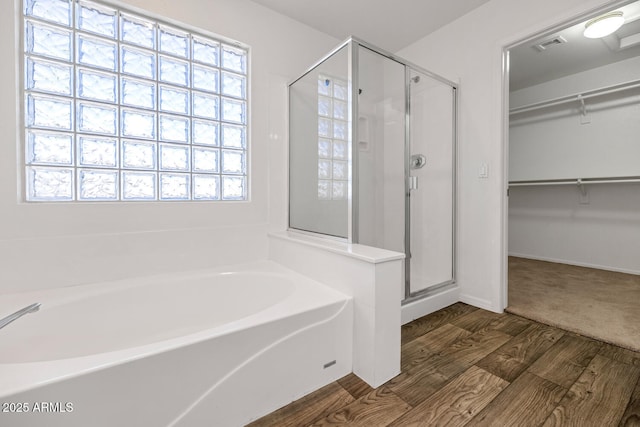 5787 W Barbara Ave, Glendale, AZ 85302 - bathroom with a bath, a stall shower, a walk in closet, wood finished floors, and baseboards