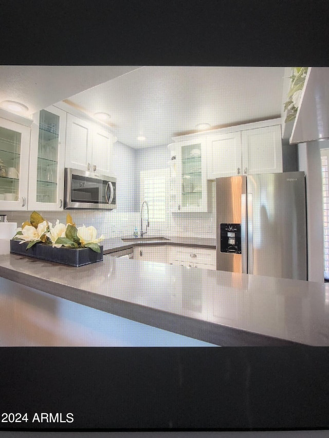 kitchen featuring sink, white cabinetry, backsplash, and stainless steel appliances