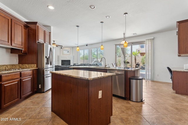 11142 E Ravenna Ave, Mesa, AZ 85212 - kitchen featuring appliances with stainless steel finishes, a kitchen island, a sink, ceiling fan, and a fireplace
