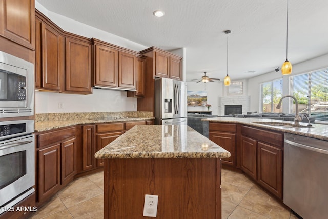 11142 E Ravenna Ave, Mesa, AZ 85212 - kitchen with appliances with stainless steel finishes, a sink, a ceiling fan, a fireplace, and a center island