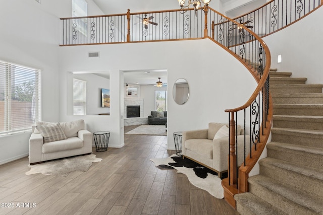 11142 E Ravenna Ave, Mesa, AZ 85212 - stairway featuring a ceiling fan, baseboards, a towering ceiling, a glass covered fireplace, and wood finished floors