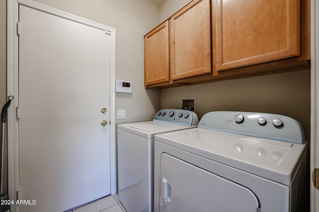 clothes washing area featuring cabinets, washing machine and dryer, and light tile patterned flooring