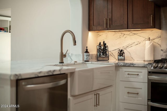 kitchen featuring stainless steel appliances, light stone countertops, white cabinets, and dark brown cabinetry