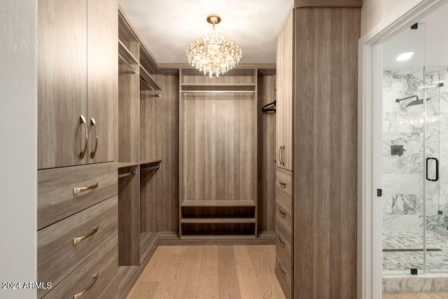 spacious closet with light wood-type flooring and a chandelier