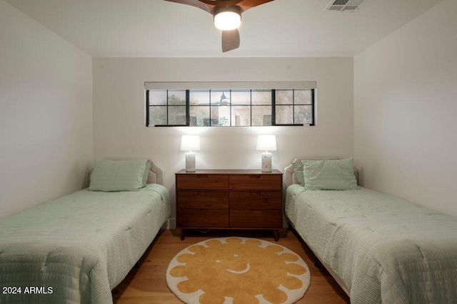 bedroom featuring hardwood / wood-style flooring, ceiling fan, and multiple windows