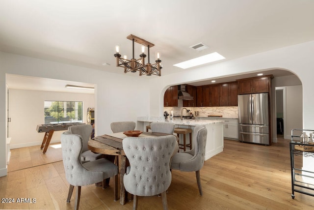 dining area featuring light wood-type flooring, a notable chandelier, and sink