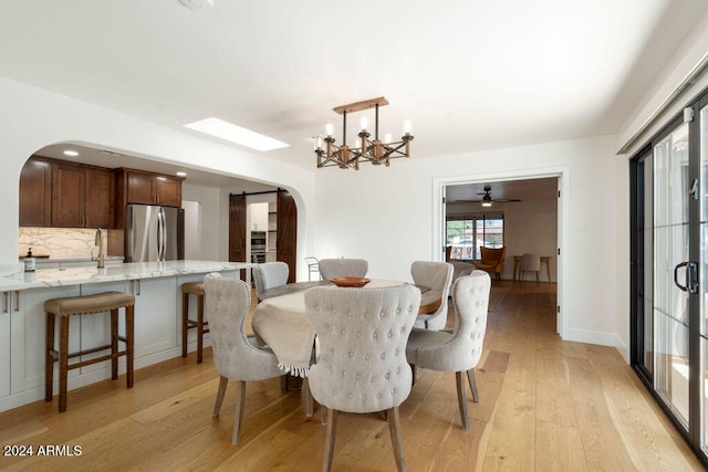 dining area featuring light wood-type flooring and ceiling fan with notable chandelier