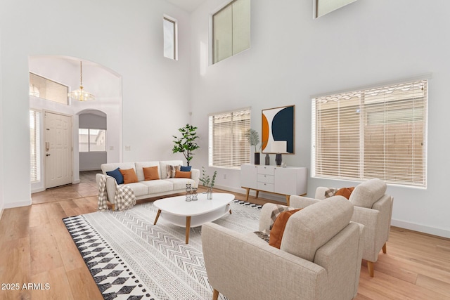 living room featuring a notable chandelier, a high ceiling, and light hardwood / wood-style flooring