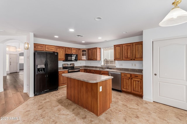 kitchen with pendant lighting, a center island, black appliances, and sink