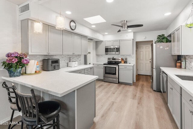 10228 W Concord Ave, Sun City, AZ 85351 - kitchen featuring stainless steel appliances, a skylight, gray cabinetry, tasteful backsplash, and light countertops