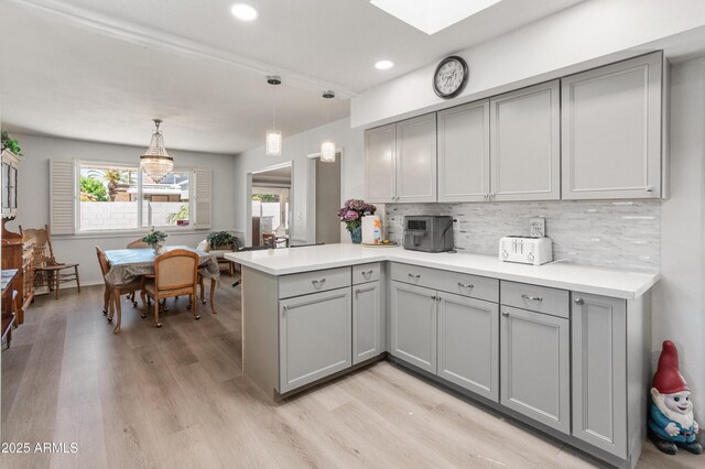 10228 W Concord Ave, Sun City, AZ 85351 - kitchen with gray cabinetry, a peninsula, light wood-type flooring, tasteful backsplash, and plenty of natural light