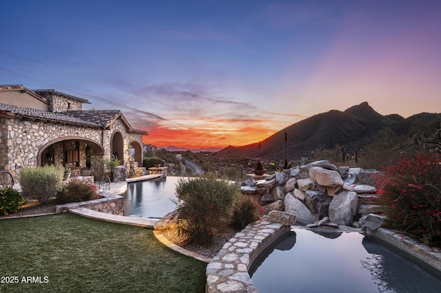 pool at dusk featuring a mountain view