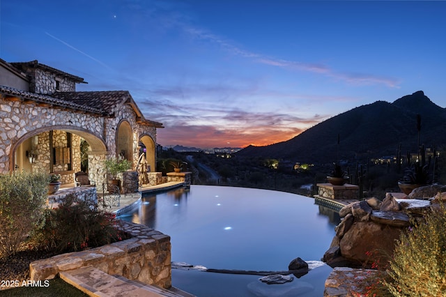 pool at dusk featuring a mountain view