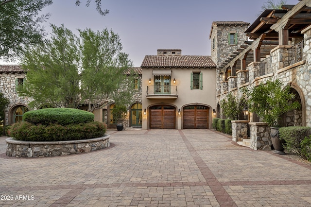 mediterranean / spanish-style home featuring a garage and a balcony