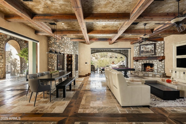 living room with beamed ceiling, ceiling fan, a fireplace, and pool table