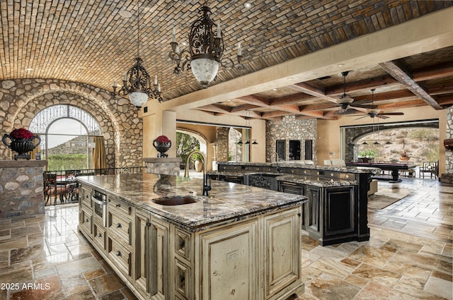 kitchen with a center island with sink, dark stone countertops, sink, and cream cabinets