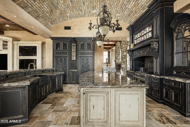 kitchen with a large island, sink, dark stone counters, lofted ceiling, and brick ceiling