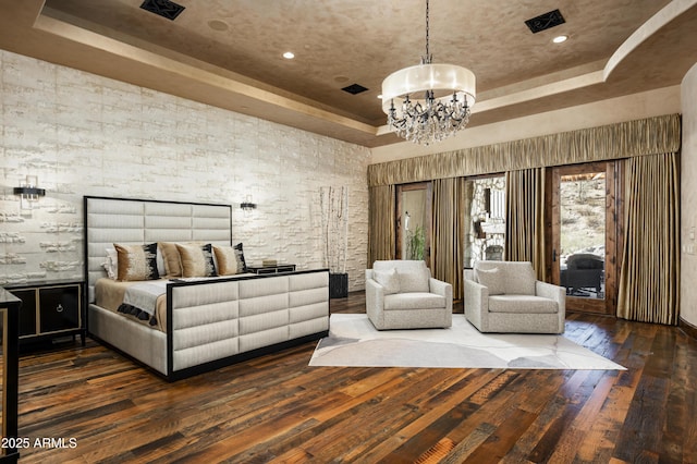 bedroom with a raised ceiling, a chandelier, and dark hardwood / wood-style floors