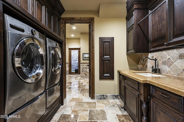 clothes washing area with washer and dryer, sink, and cabinets